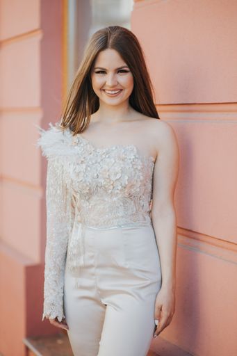 A vertical shot of a Caucasian female with beautiful jumpsuit posing outdoors
