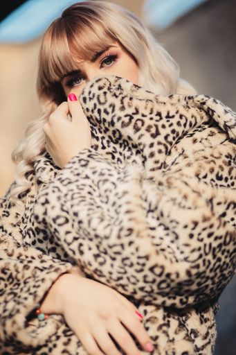 A vertical shot of a young blonde female posing in a brindle coat