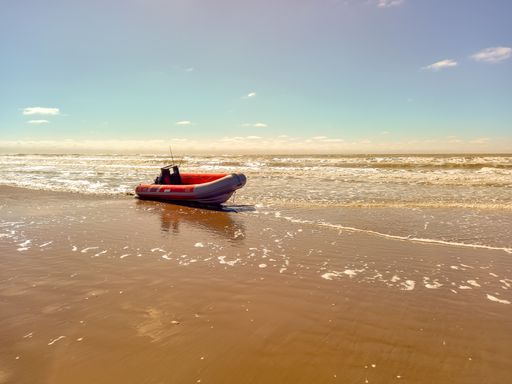 A rigid hull inflatable boat with outboard motor in the shore beaten by the waves. Used to fish at sea. Copyspace. Mar de Ajo, La Costa, Argentina
