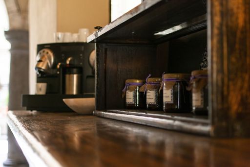 A closeup shot of a brown wooden shelf with jars of ingredients and a coffee machine in kitchen