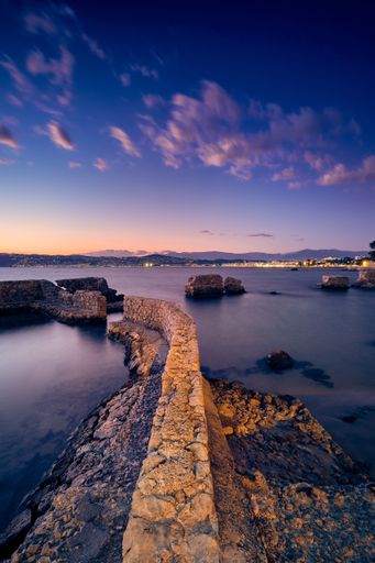 A vertical picture of the sea surrounded by Antibes during the evening in France