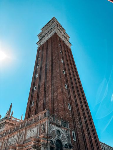 A majestic building with a clock tower standing tall against a vibrant blue sky, its facade illuminated in the sunshine
