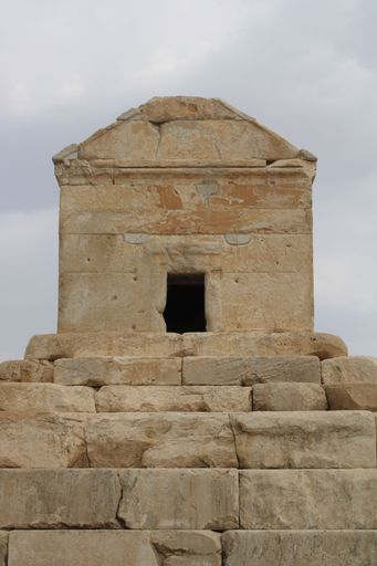 A majestic stone structure with an open archway stands atop a rocky outcropping, overlooking a peaceful landscape