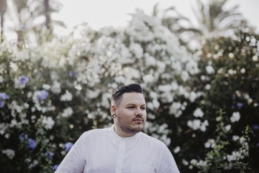 A young man wearing a white shirt and flowers on the background