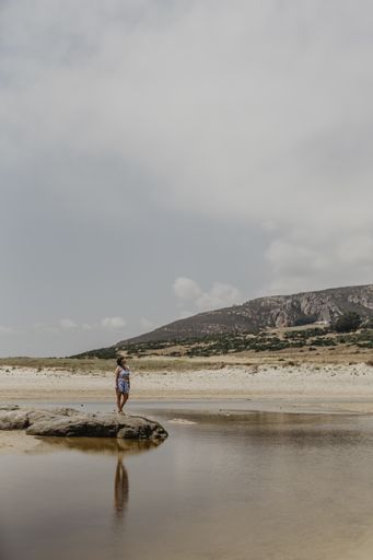 A vertical shot of a woman standing in the sandy beach