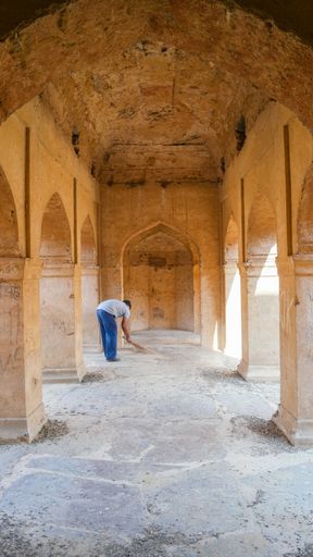 a vertical shot of a male cleaning the stone ground of Neemrana Fort-Palace in Rajasthan, India