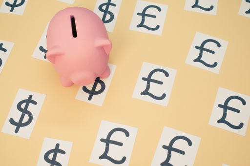 A top view of a pink piggy with a currency symbol on a brown background