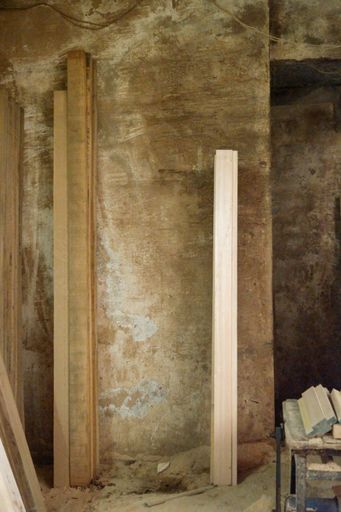 A vertical shot of narrow wooden boards leaned on the wall