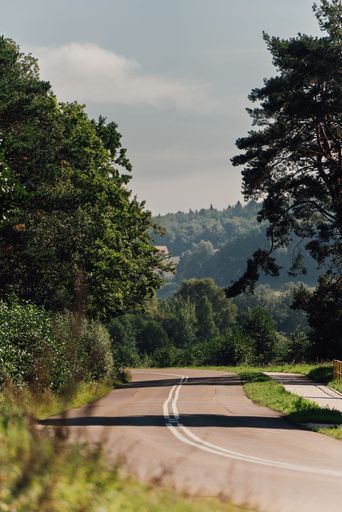 A vintage-style motorcycle is parked on a winding country road, with rolling hills in the background