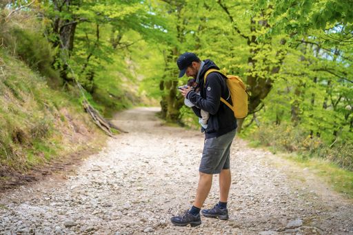 A young father walking with his newborn child on a path in the woods