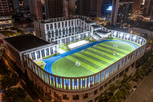 An aerial view of an illuminated soccer field on a tall building roof