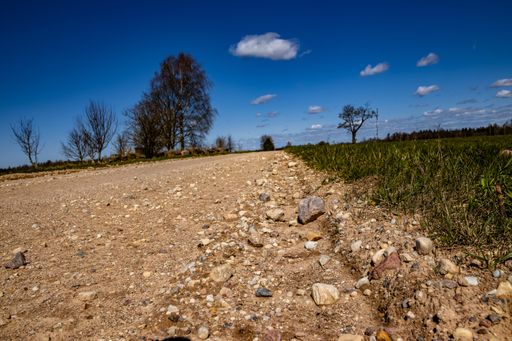 A closeup of a dirt road through the countryside under a blue sky