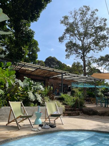 A sun-soaked outdoor patio with lounge chairs in front of a sparkling blue swimming pool
