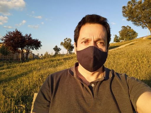 A closeup shot of a Caucasian man wearing black mask in a green field