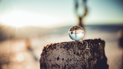 A selective focus shot of a small glass globe on a trunk with a desert in the background