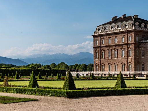 The Palace of Venaria surrounded by greenery and rocky mountains under the sunlight in Italy