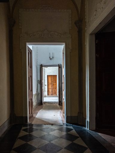 A vertical picture of a dark old corridor of a house with open doors