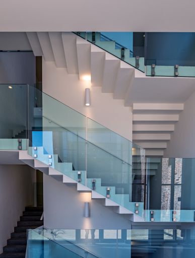 A modern staircase with glass handrails surrounded by lamps in a modern building