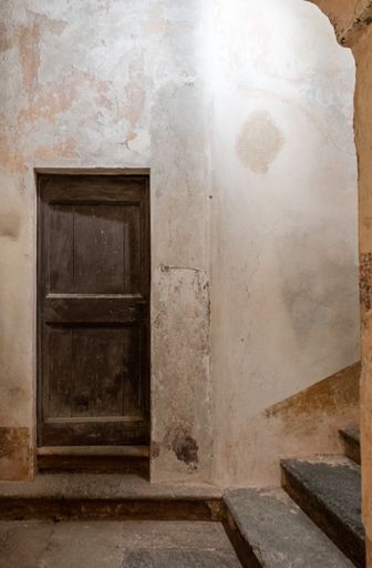 A vertical picture of an old wooden door in an abandoned building under the lights