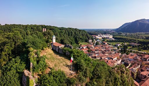 A high angle view of a town surrounded by hills covered in greenery under the sunlight in Italy