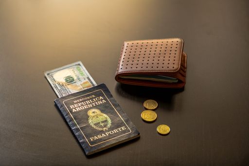 An Argentine passport with dollars and euros with a brown wallet and a credit card on a table