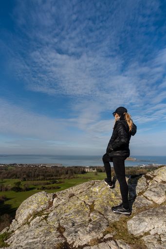 A woman on a mountaintop admiring the scenery of the Howth Dublin bay in Ireland