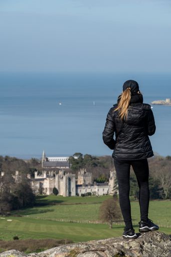 A woman on a mountaintop admiring the scenery of the Howth Dublin bay in Ireland