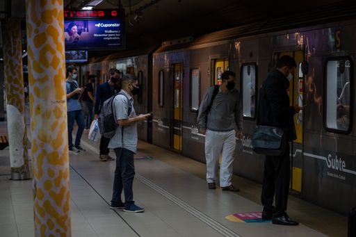 people waiting for the arrival of the subway train on the platform with social distancing