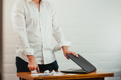 A closeup shot of a white Caucasian man closing his laptop after a long working day