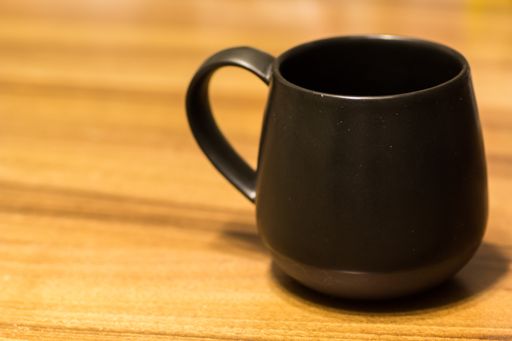 A black mug put on a wooden surface during daytime