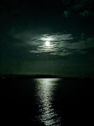A vertical shot of a glowing moon in the ocean