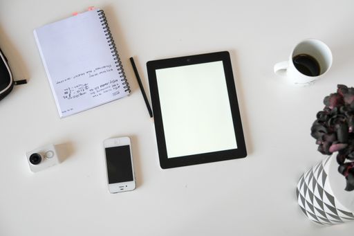 A top view of a tablet with a notebook on a white surface