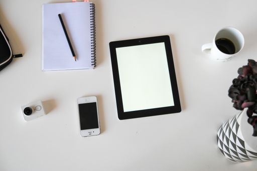 A top view of a tablet with a notebook on a white surface