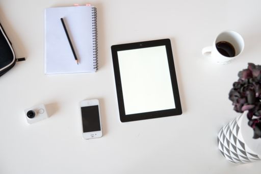 A top view of a tablet with a notebook on a white surface