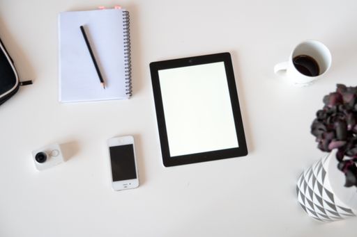 A top view of a tablet with a notebook on a white surface