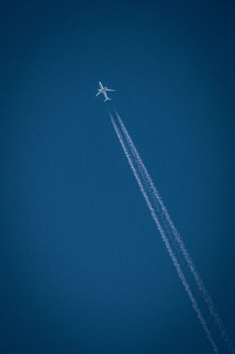 A vertical shot of a passenger airplane at cruising altitude against blue sky