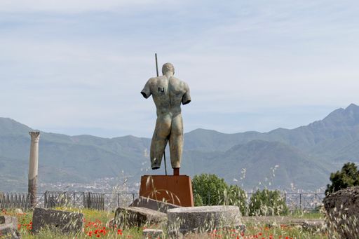 A beautiful statue in forum at pompeii with an overlooking view of mountains in italy