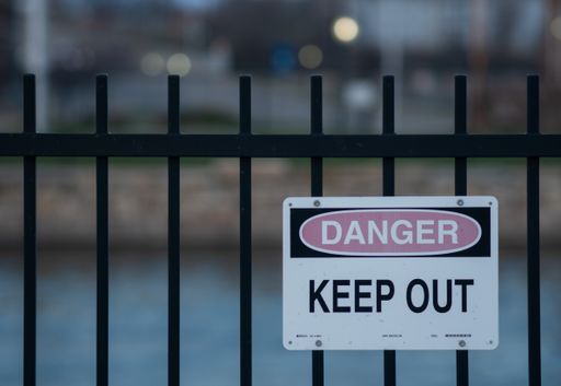 A closeup shot of a warning sign ''danger, keep out'' on the metal fence