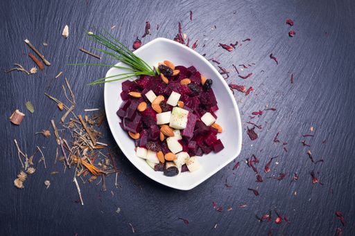 A top view of a salad made with vegetables served in a white plate on a blue table