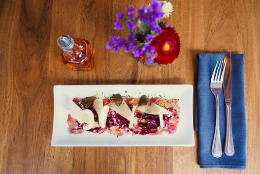 A top view of a salad made with vegetables served in a white plate on a wooden table