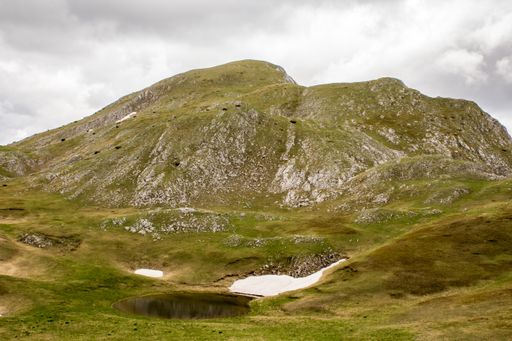 A small mountain lake in a valley under the cloudy sky