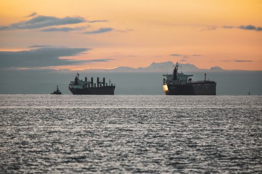 A vertical shot of the old ship in a lake with mountains in the background during sunset