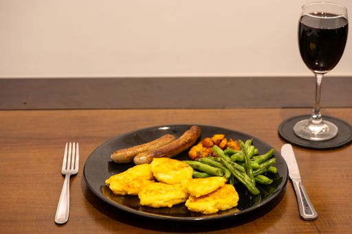 A nutritious meal of fresh vegetables and eggs served on a black plate, accompanied by a glass of wine