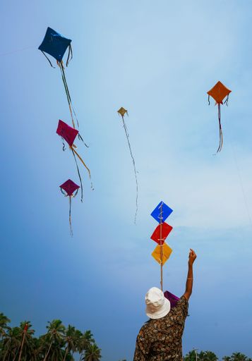 A cheerful man enjoying a sunny day at the beach while playing with kites