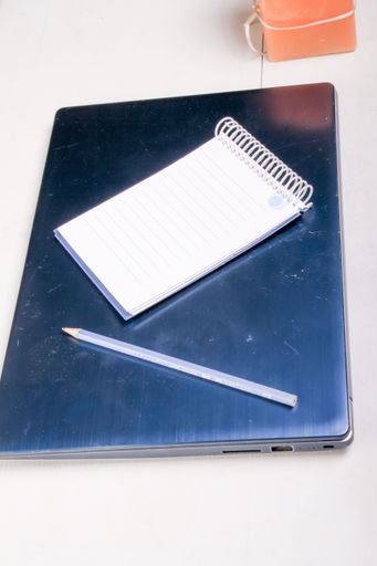 A vertical shot of a notepad and pencil on a closed  laptop