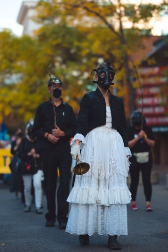 A climate change activist in a white dress and a gas mask leads a protest against the World Petroleum Congress