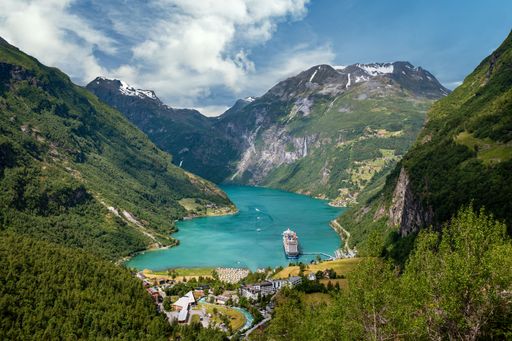 A scenic view of a tranquil lake surrounded by lush vegetation and a majestic mountain range in the background
