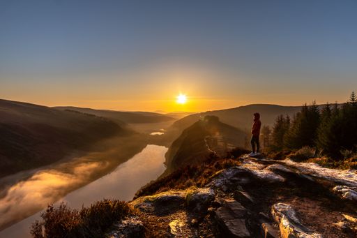 A male standing on the Spink Viewing Spot admiring the sunrise in Wicklow, Ireland