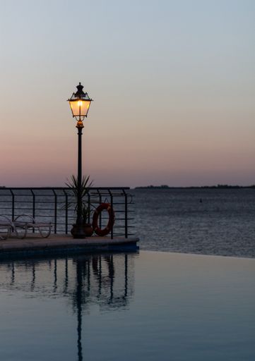 A vertical shot of a vintage street lamp by the pool against a cloudless beautiful sunset sky