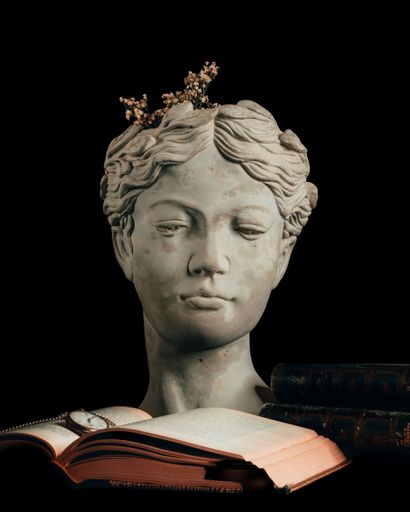 A stone Greek statue of a female with flowers on the head and a book in the foreground on the black background